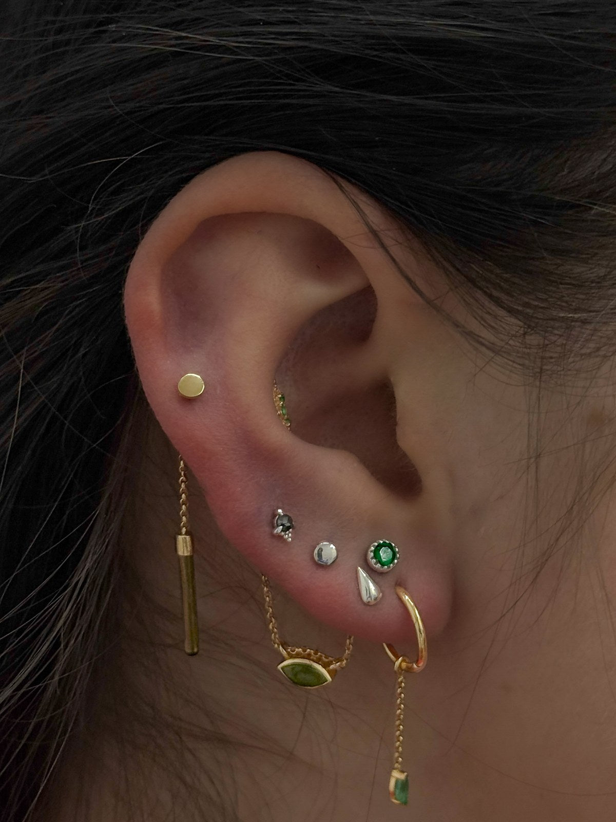 Curated ear with mixed gold and green gemstone jewelry
